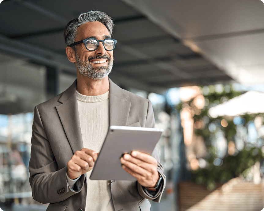 Man in suit using tablet, smiling outdoors.